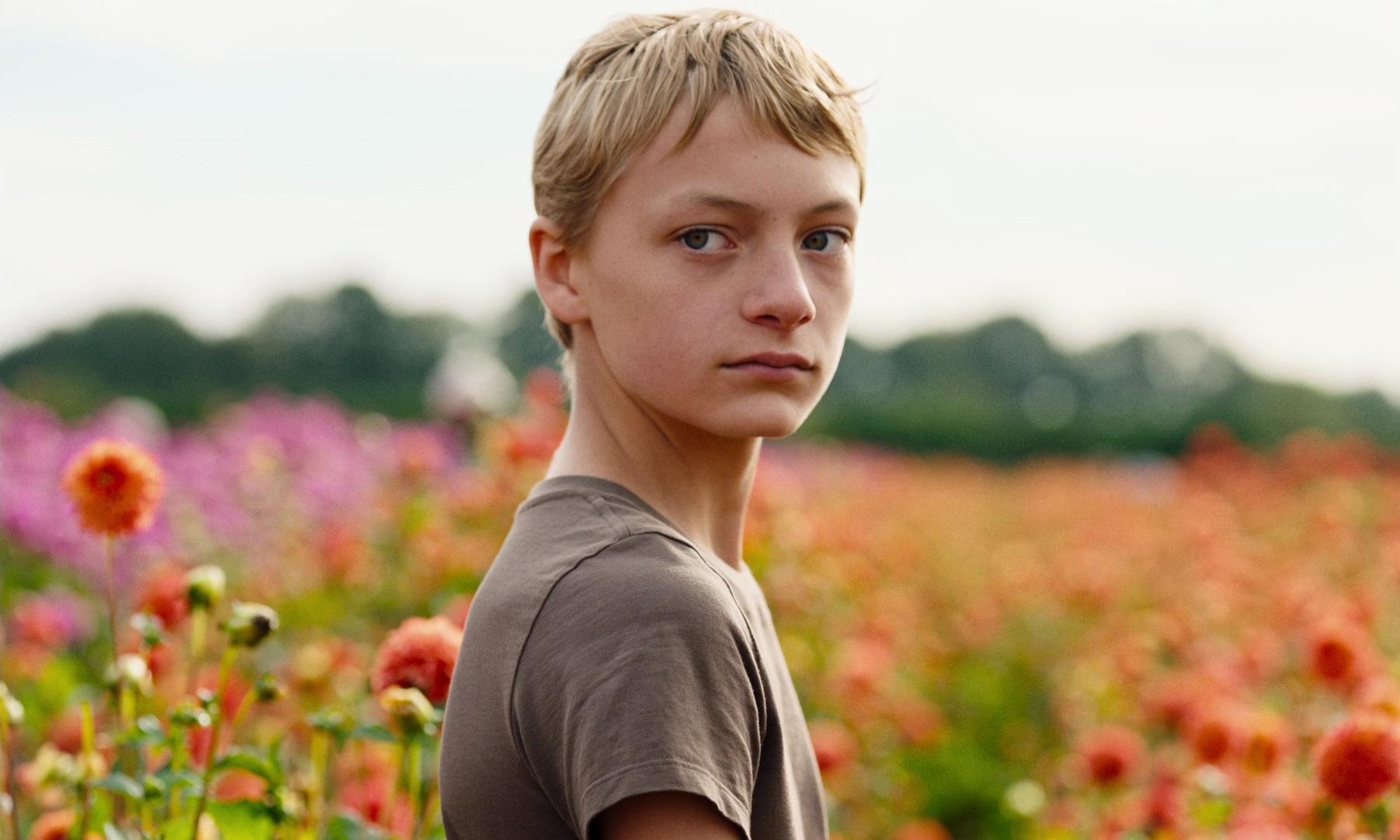 Leo from the movie Close standing in a flower field